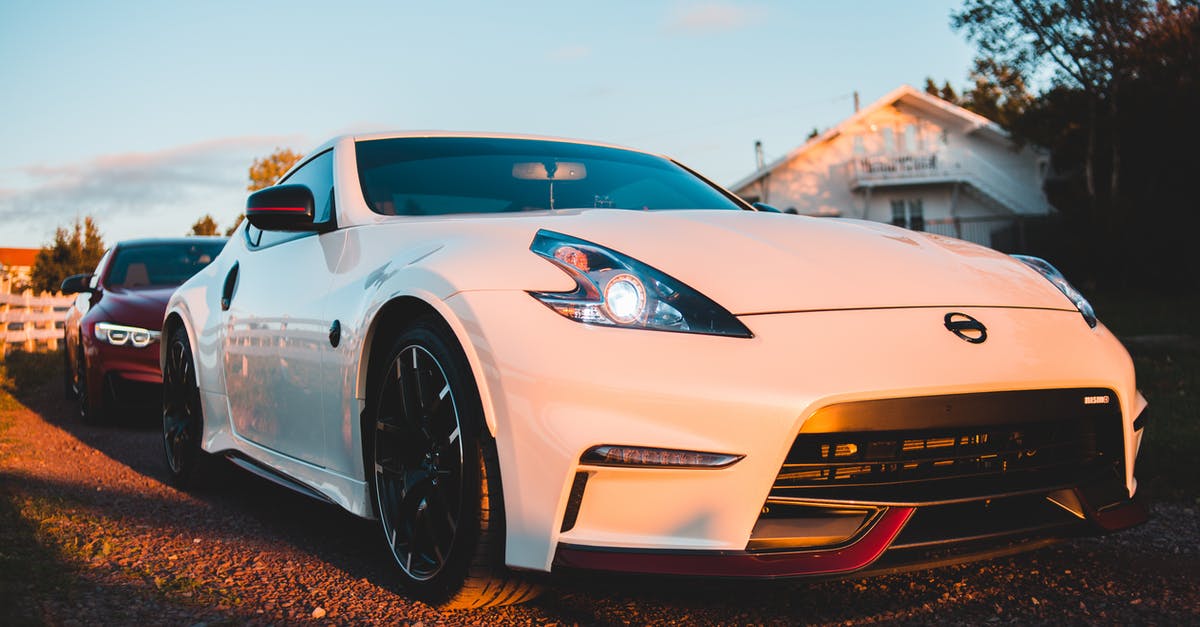 How expensive is a vacation to Japan? - Luxury white sports car with glowing headlights parked on rough road near small houses against blue sky in countryside