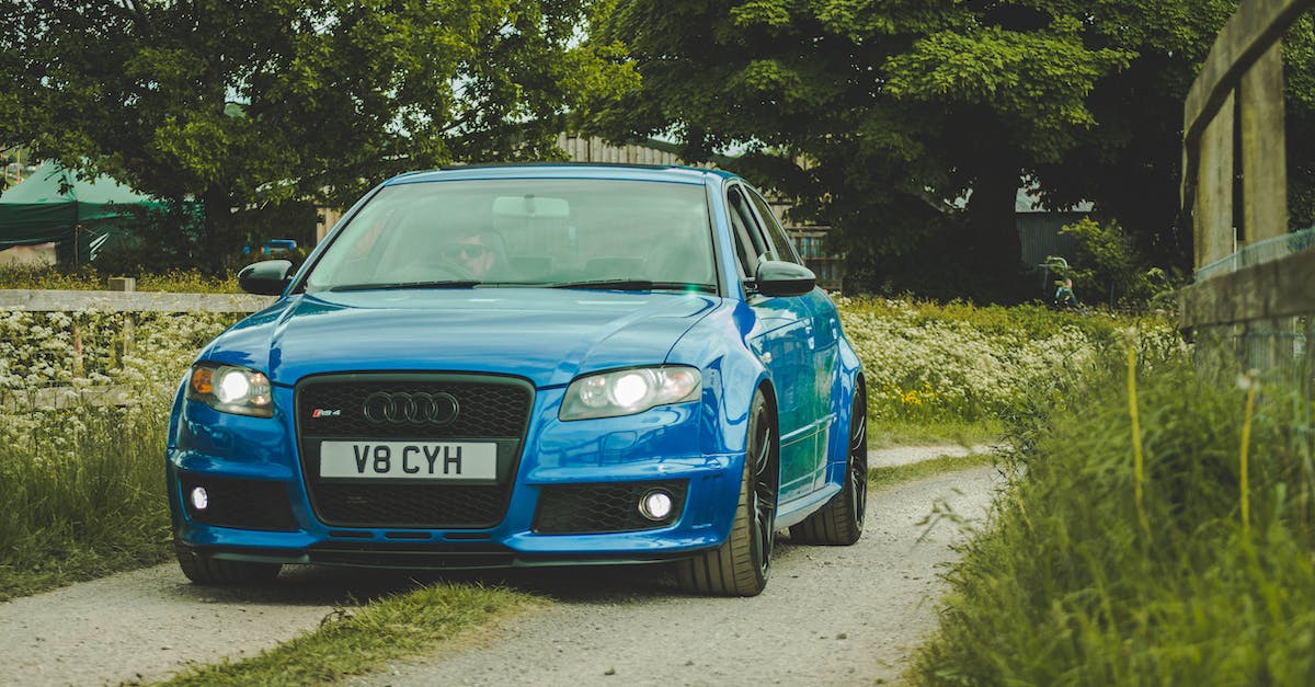 How expensive is Belgium? - Blue Audi Car Moving on the Street Between Green Grasses