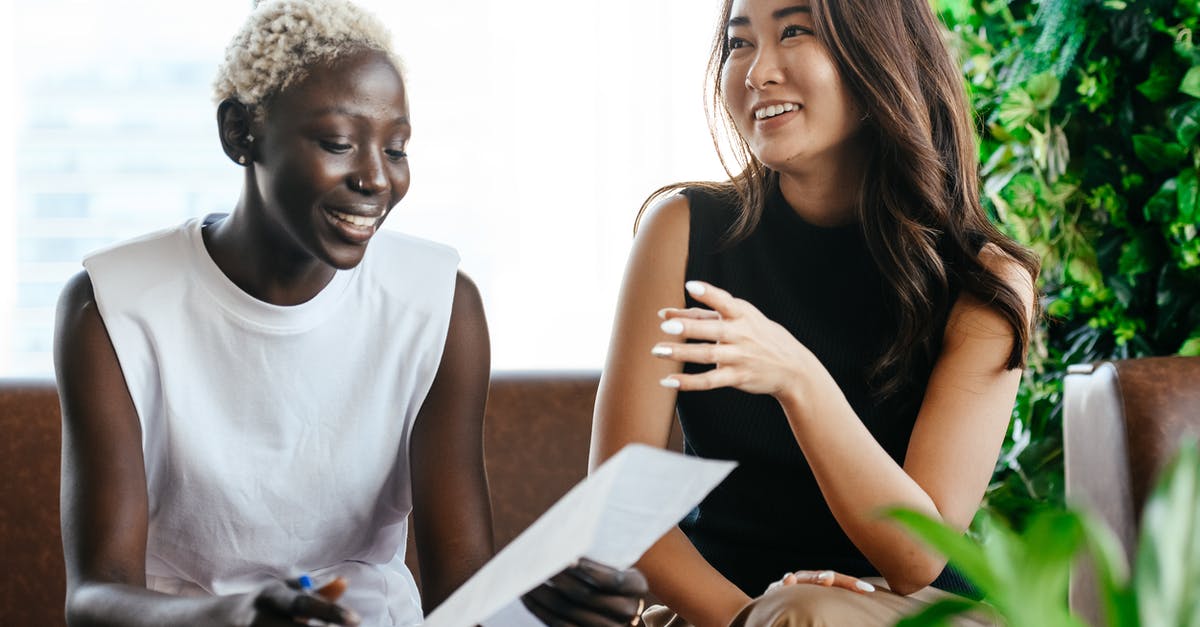 How friendly is the Netherlands to vagabonds? - Multiethnic happy smiling women checking papers while speaking in comfortable conference hall in daytime