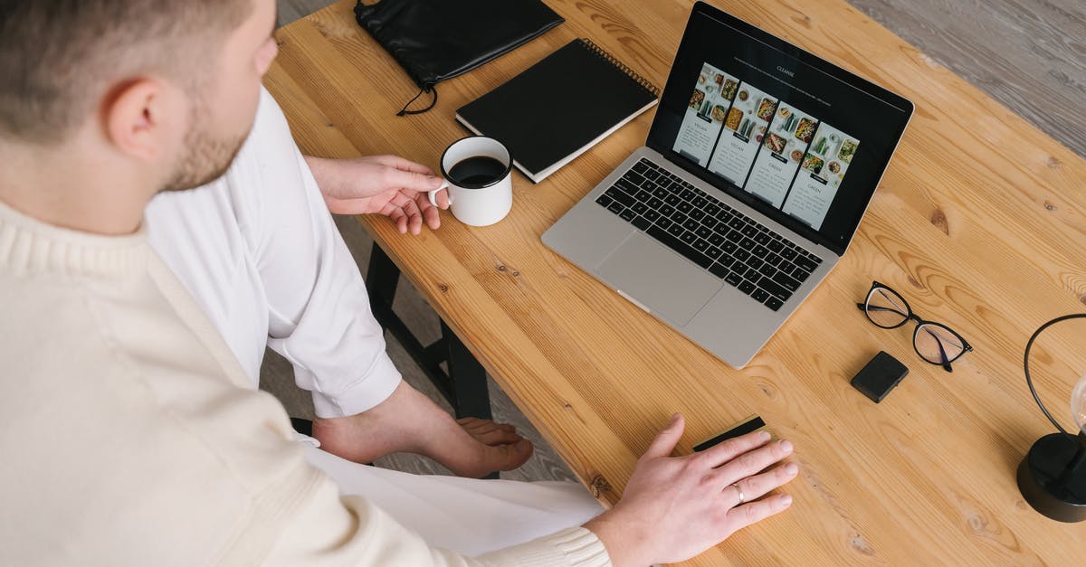 How good is credit card acceptance in Czech Republic? - Man in White Long Sleeve Shirt Sitting on Chair in Front of Macbook Pro