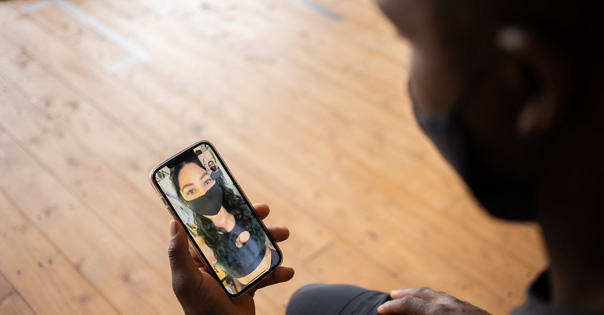 How is Venice during COVID times? - Crop black man talking to girlfriend in mask on smartphone