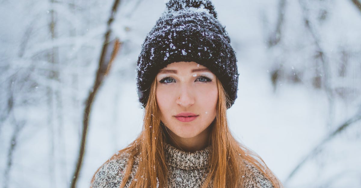 How long can I park in the blue zone in Switzerland? - Woman in warm knitted sweater and hat standing in winter forest