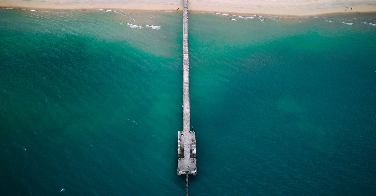How long does it take to bike to Marken Island from Amsterdam - Drone view of long pier near sandy shore washed by turquoise water of blue endless ocean