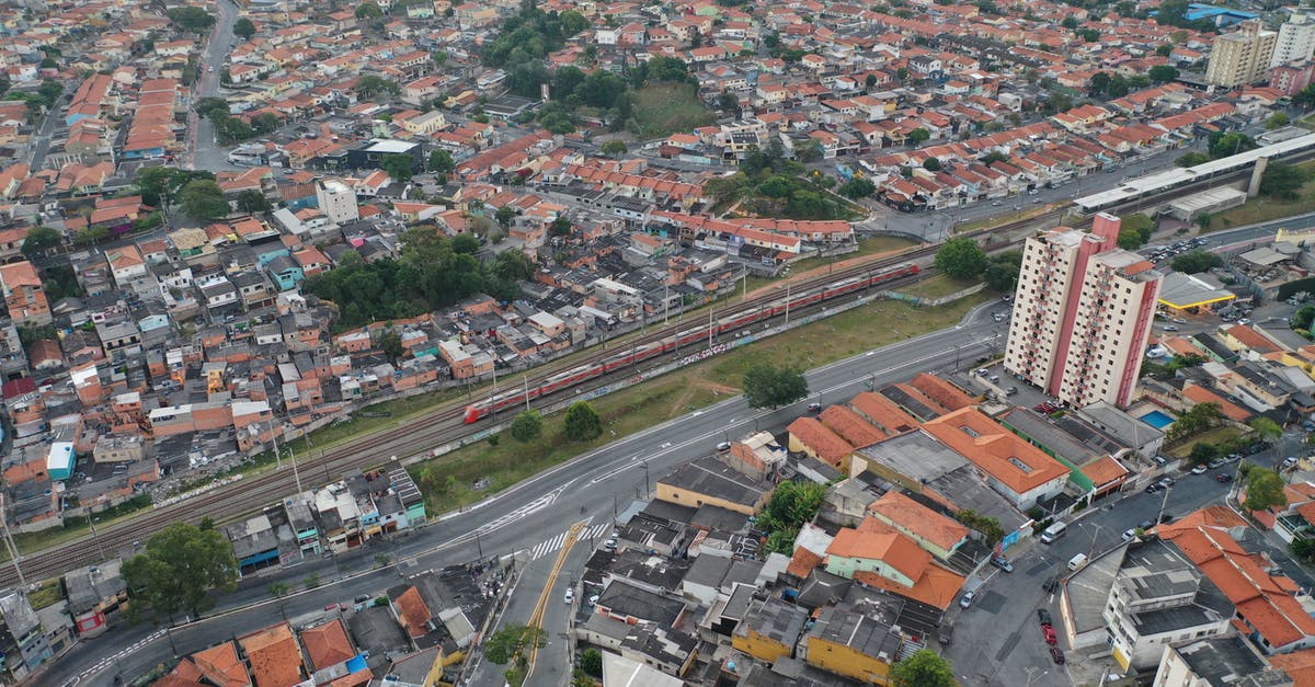 How long from flight arrival to train travel at Heathrow T2 - Drone view of tall buildings and cottages near road and long railway in populated province