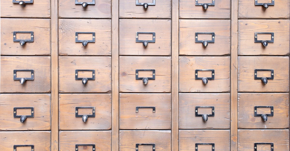 How long should I keep my old passport? - Background of wall full of many similar aged shabby vintage wooden drawers with metal round handles