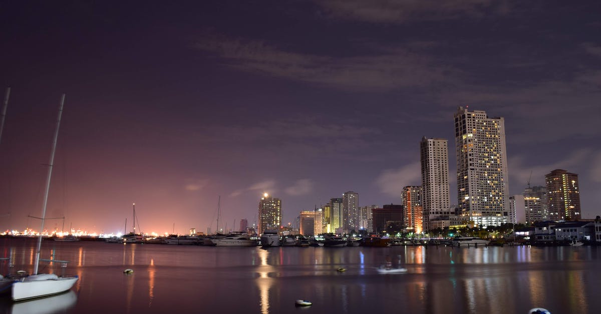 How long should I schedule to travel from Manila to General Santos, Philippines? - Low angle of modern boats moored in harbor of Manila with contemporary illuminated skyscrapers against evening sky