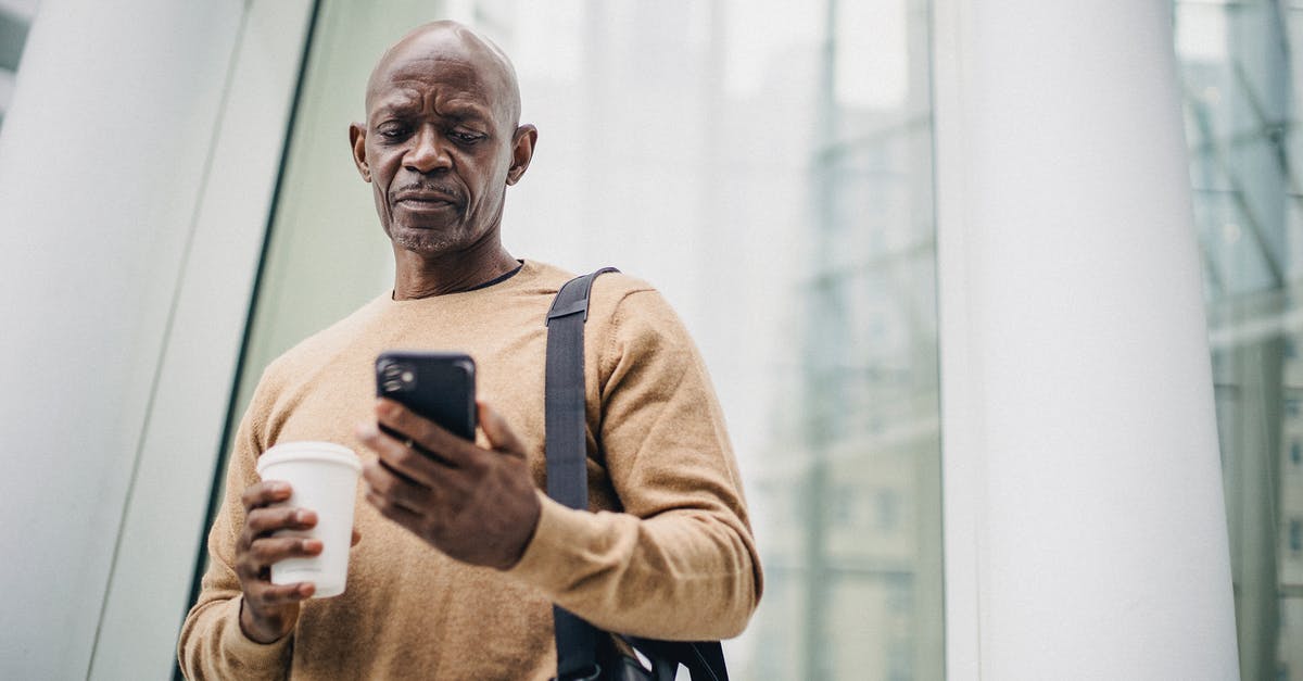 How manageable are <15 min connection times in Frankfurt Hbf? - Focused mature black man chatting on smartphone during coffee break on street