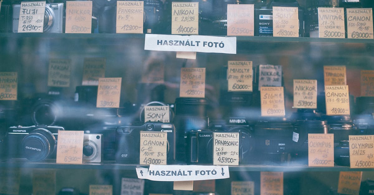 How many hours are on a transit visa through Canada? - Through glass collection of various photo cameras placed on local store showcase with paper price label and inscriptions