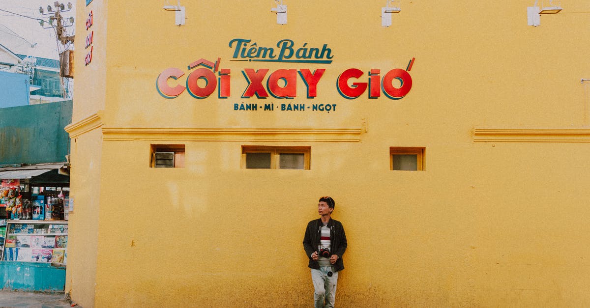 How much does a tourist visa for Vietnam cost? - Man Standing Beside Yellow Concrete Building