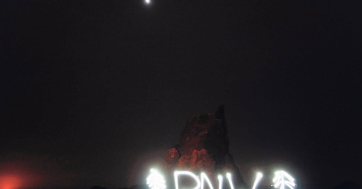 How much does it add to a North America / Australia journey to go "the wrong way"? - Abbreviation PNW between fir shaped decorations illuminating with white neon lights and located against rocks at night under dark sky and bright moon Pacific Northwest traveling