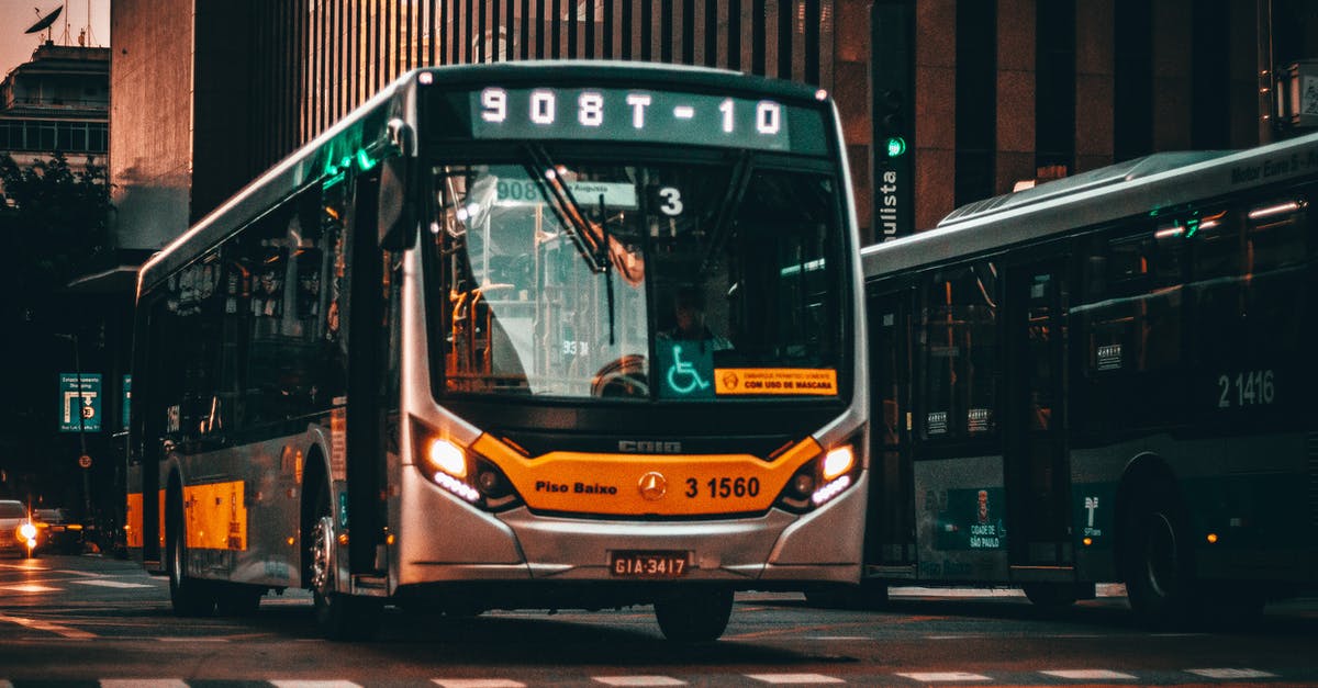 How much is a bus from Buenos Aires to Rio de Janeiro? - Low angle of modern bus riding on asphalt road amidst building of contemporary city at sunset