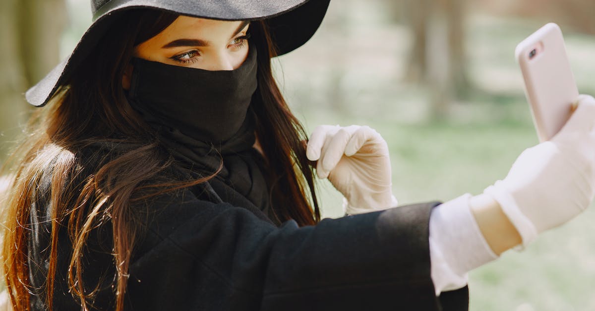 How practical is it to take a Collectivo to Xel'Ha park? - Crop female in stylish outerwear and medical mask and gloves taking selfie on smartphone in park during walk on city street