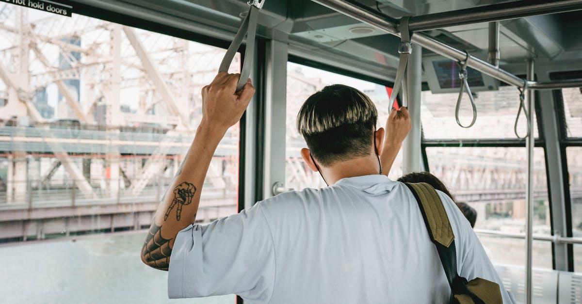 How safe are cable cars? - Back view of anonymous male with modern haircut and backpack near partner in cable cabin during trip over river