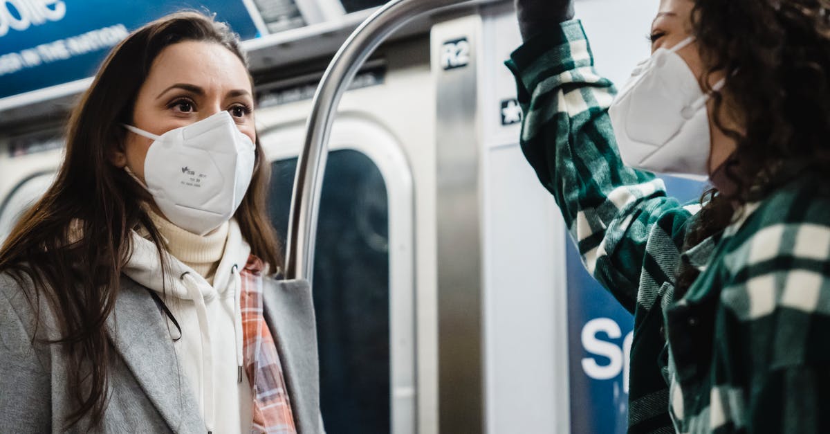 How Safe are Train Rides in the U.S.? - Content diverse female friends wearing outerwear in protective masks riding in subway train together during pandemic while commuting in metro