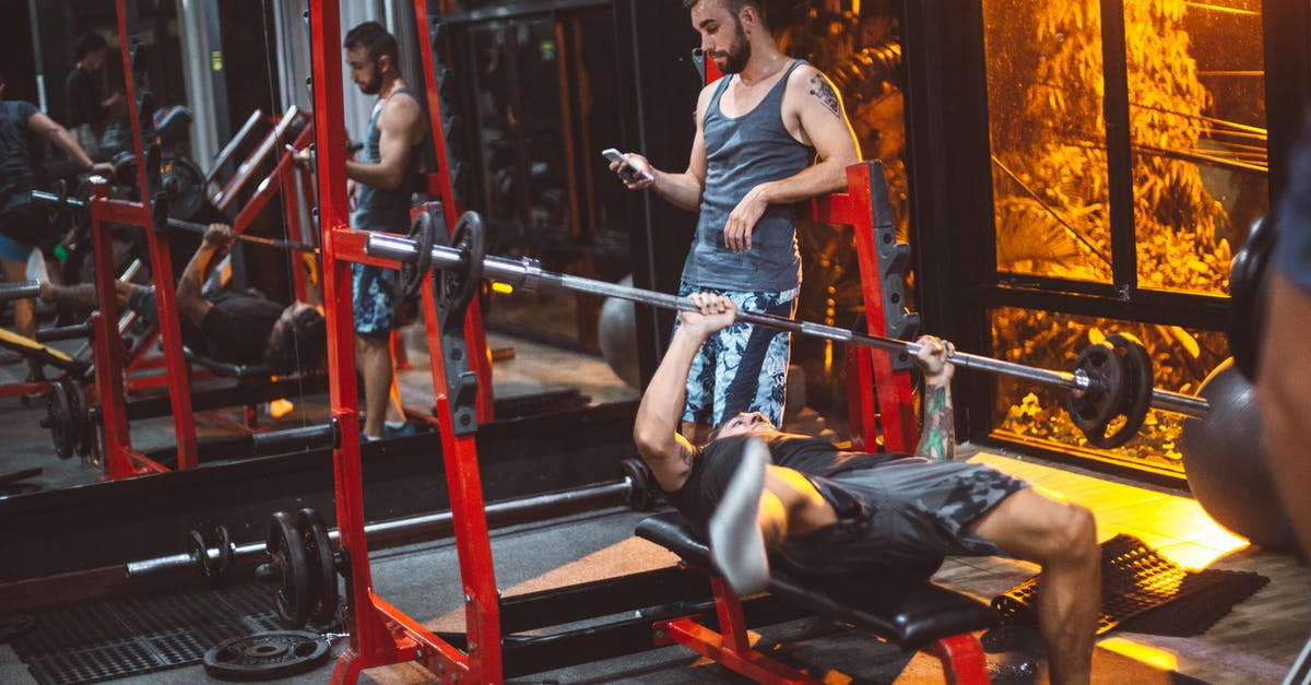 How to activate mobile phone in Chile? - Sporty fitness trainer and man lifting barbell