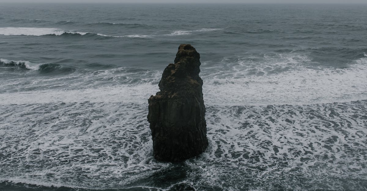 How to assess rough water severity? - Severe rough rock formation located in shallow sea washed by foamy waves under gloomy sky