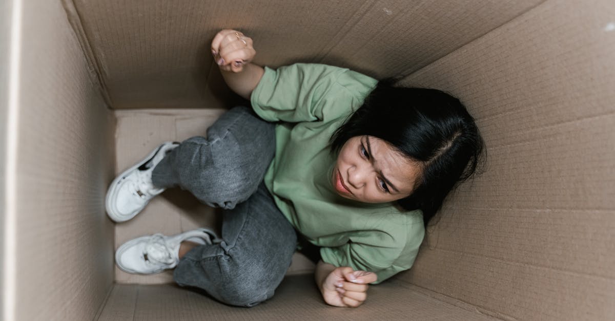 How to avoid claustrophobia on a plane? - A Fearful Woman Having Claustrophobia in a Cardboard Box