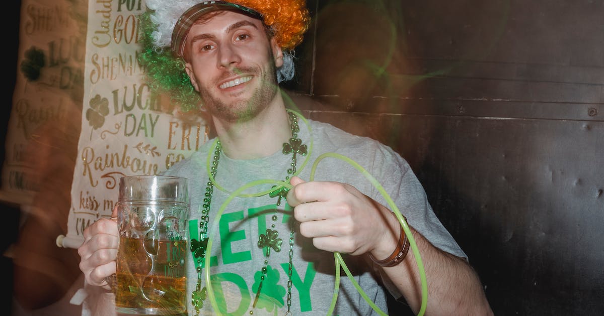 How to avoid having my drink spiked in a bar - Joyful young guy with beer glass celebrating St Patricks Day in pub