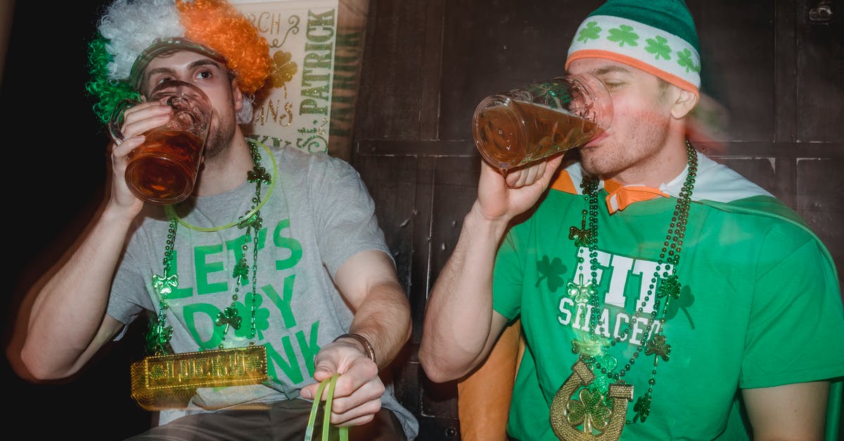 How to avoid having my drink spiked in a bar - Delighted young friends wearing Irish national symbols emerald green hat and party wig in flag colors and necklace and neon green glow sticks drinking beer while enjoying Saint Patrick Day celebration