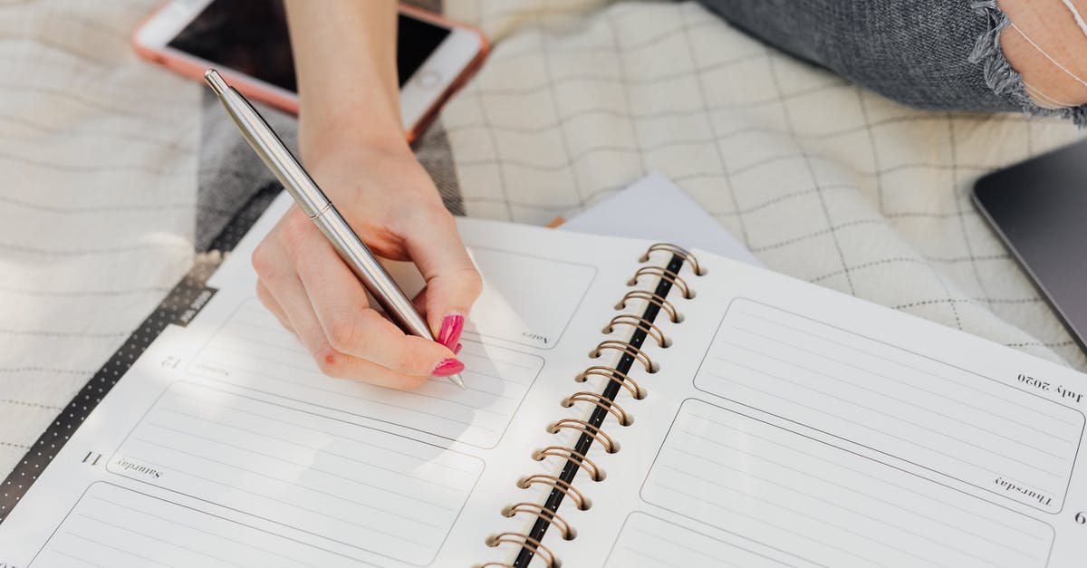 How to avoid the the multitudes during Obon week in Japan? - Crop faceless lady in jeans writing in notebook with mobile phone beside while sitting on picnic blanket on sunny day in park