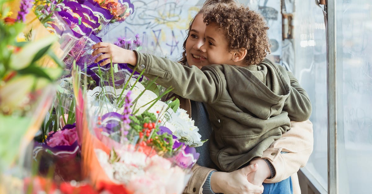 How to Buy Machu Picchu Tickets for Children Online? - Smiling mother holding cute black son on hands while choosing together bouquet in floristry store