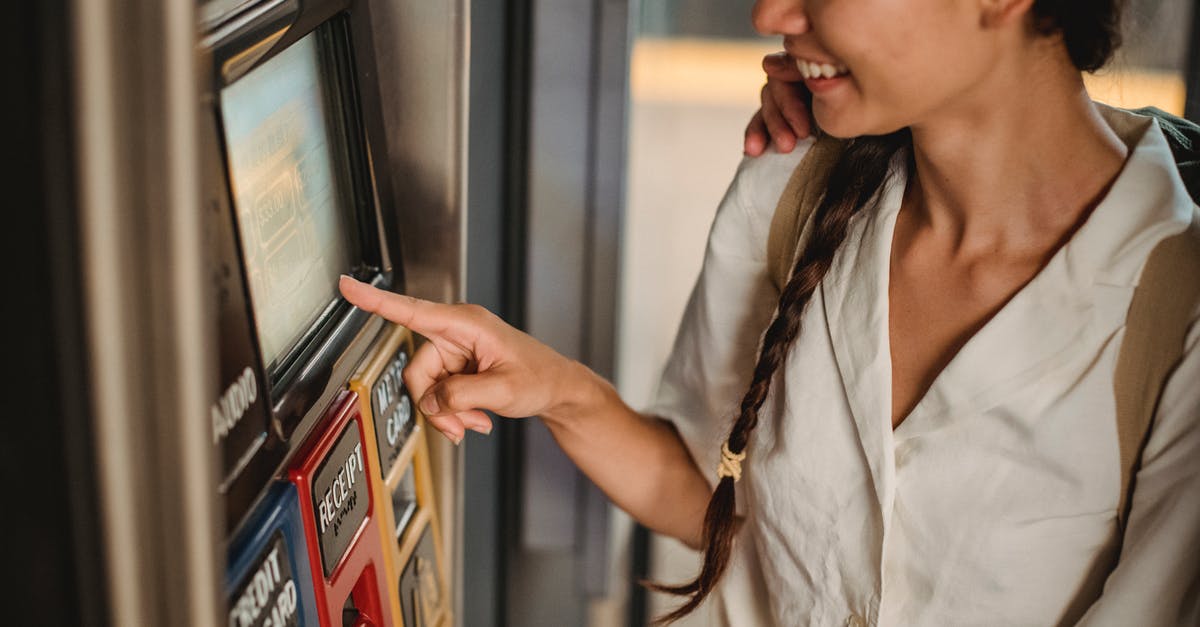 How to buy tickets for Machu Picchu? - Crop smiling Asian female in white shirt using ticket vending machine with touch screen in underground