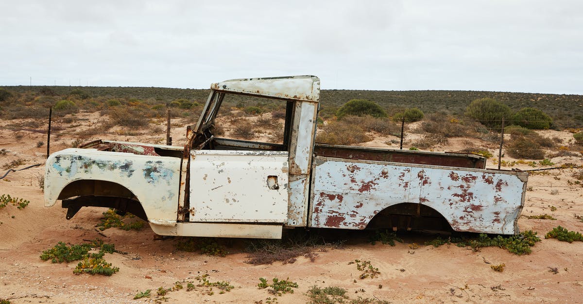 How to calculate the damage to a rental car? - Rusty abandoned car near fence in desert