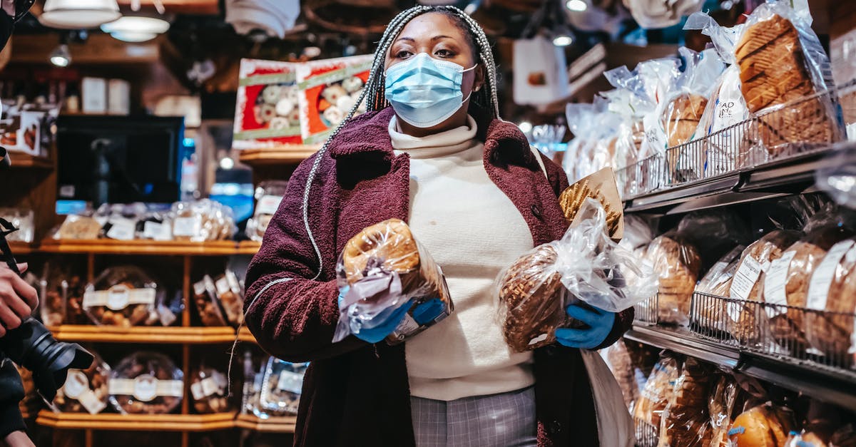 How to carry honey jars and prevent losses? - African American female buyer in protective mask and gloves carrying loafs of bread in grocery store