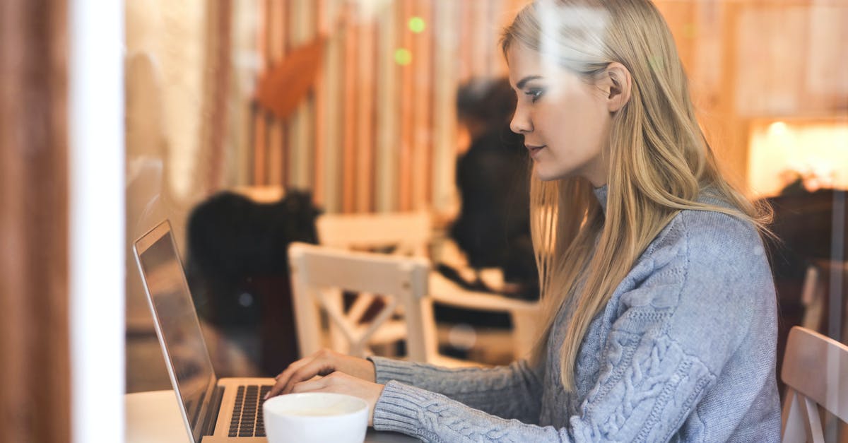 How to change my loyalty program online before check-in? - Serious young woman using netbook while having hot drink in modern cafe