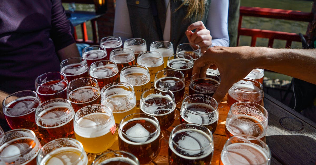 How to choose a foreigner-friendly bar in Shinjuku Golden Gai - High angle of crop faceless friends tasting various types of craft beer while relaxing together in street cafe on sunny day