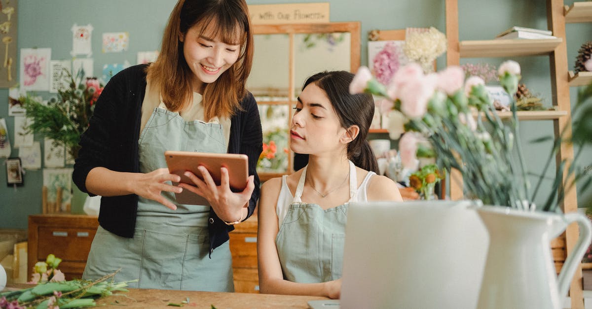 How to choose seat with JAL when online check-in is not available? - Content multiethnic female coworkers at table with flowers surfing tablet while choosing design for bouquet during work in florist shop