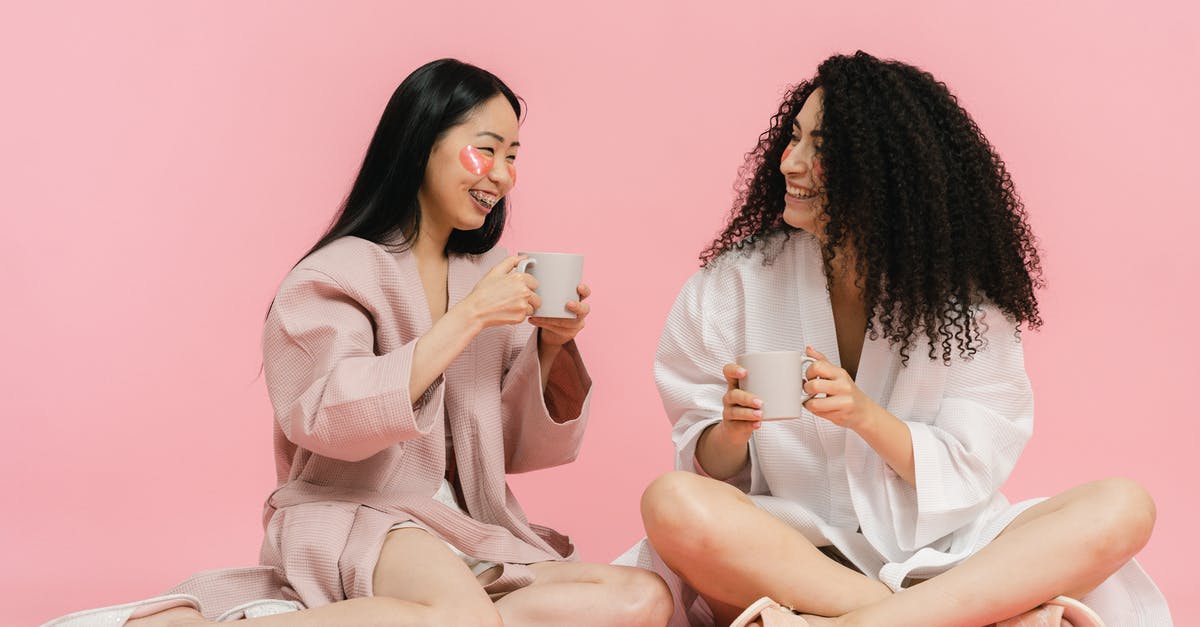 How to choose where and how long to have my layover - Two women in bathrobes sitting on floor and having break with cup of tea