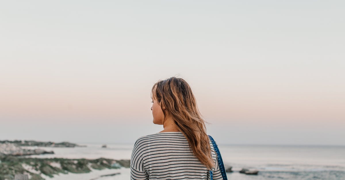 How to cope with disgusting fellow travellers? - Woman in Black and White Striped Long Sleeve Shirt Standing on Beach