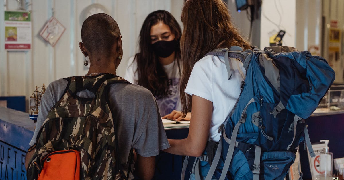 How to discover if a hostel is more a travel hostel or a party hostel? - Two Women with Travelling Backpacks Checking In On Reception Desk