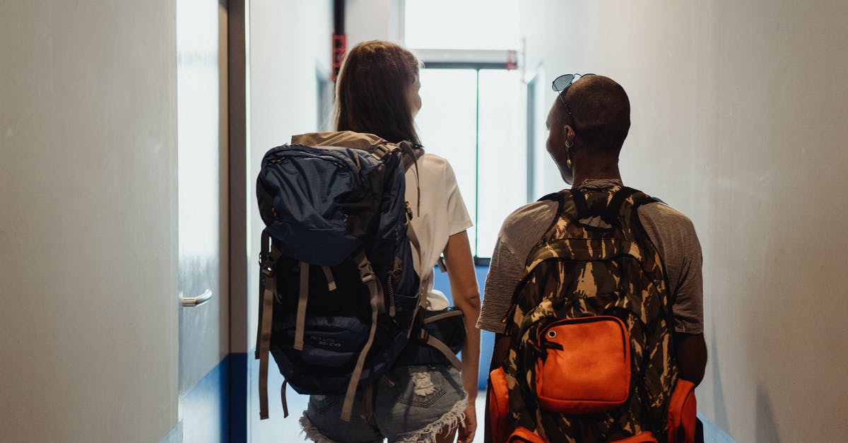 How to discover if a hostel is more a travel hostel or a party hostel? - Women with Backpacks Walking Through the Hostel Corridor