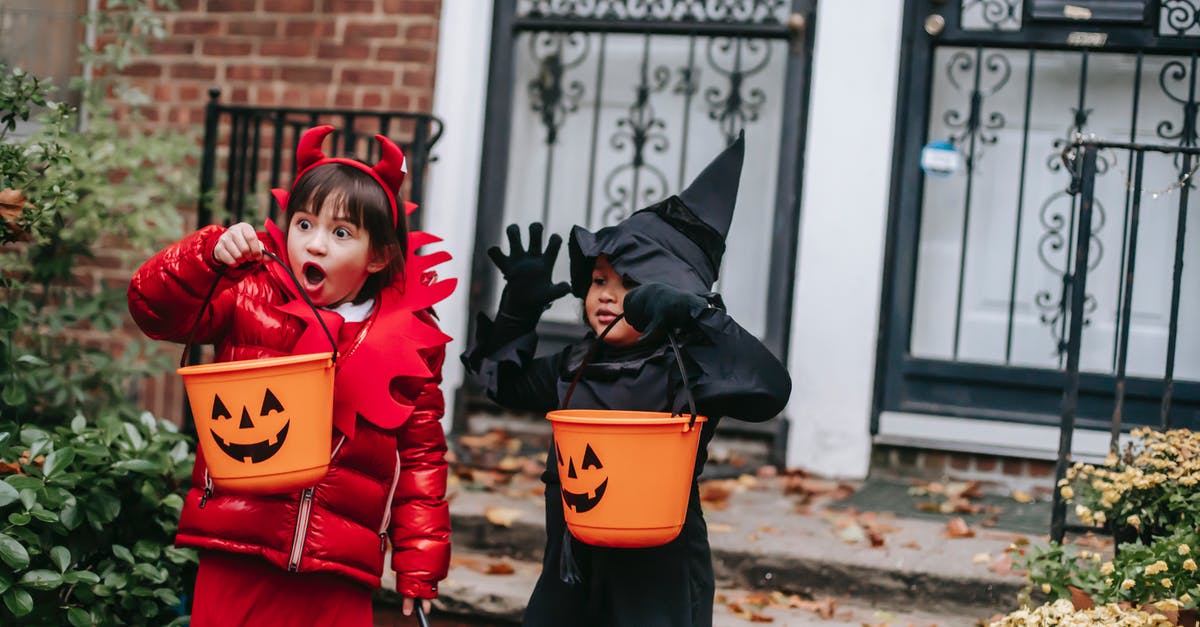 How to dress for Himachal Pradesh in October? - Funny children in witch and devil costumes carrying buckets for candies and showing creepy grimaces against house in neighbourhood