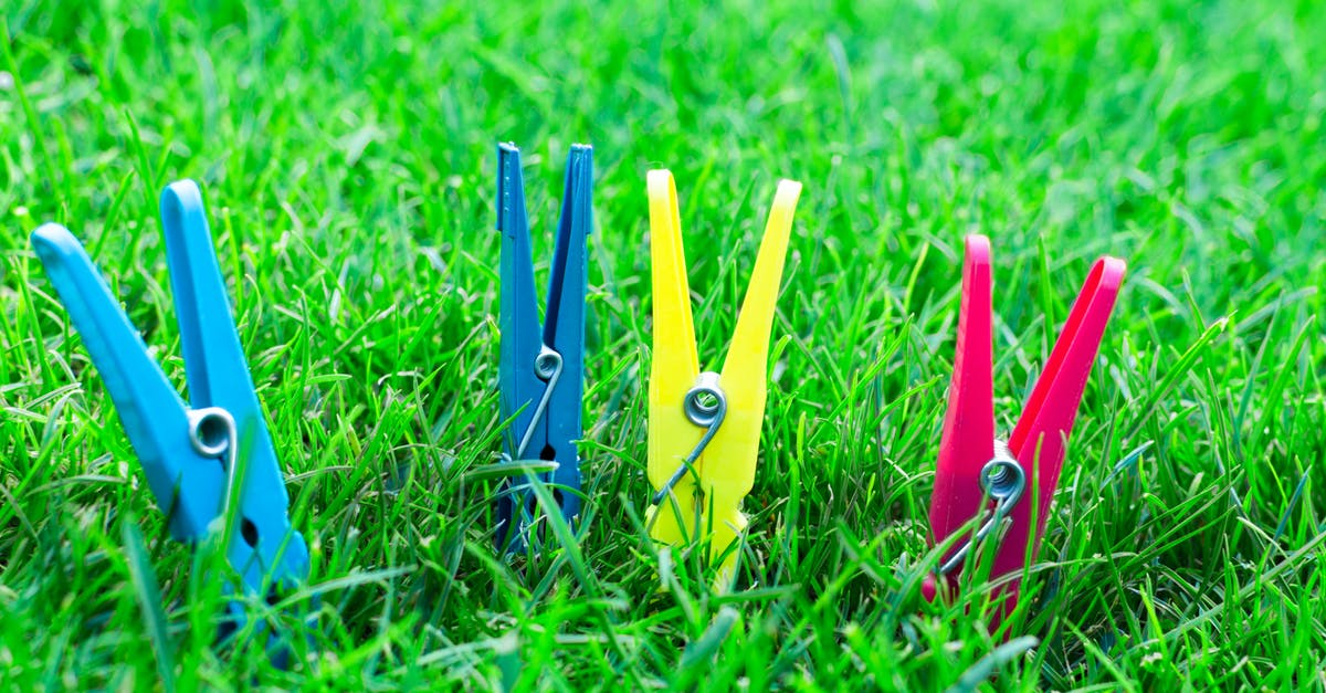 How to dry clothes while travelling in winter? - Two Blue One Yellow and One Pink Clothes Clips on Green Grass