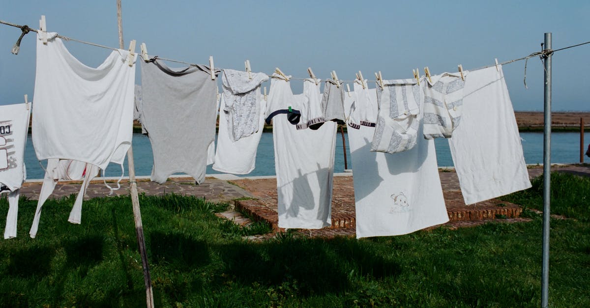 How to dry out a wet passport? - Drying washed laundry hanging on clothesline between poles on grassy seashore on sunny summer weather