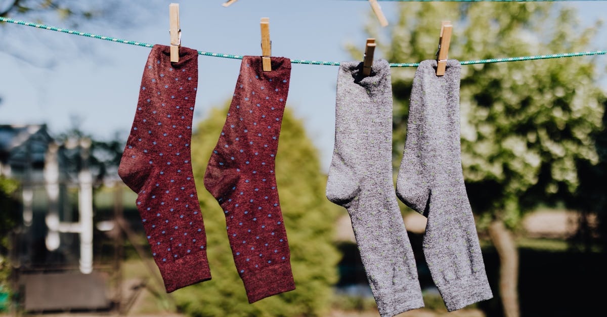 How to dry out a wet passport? - Soft focus of washed multicolored socks hanging on rope with clothespins outdoors on sunny summer day against natural background