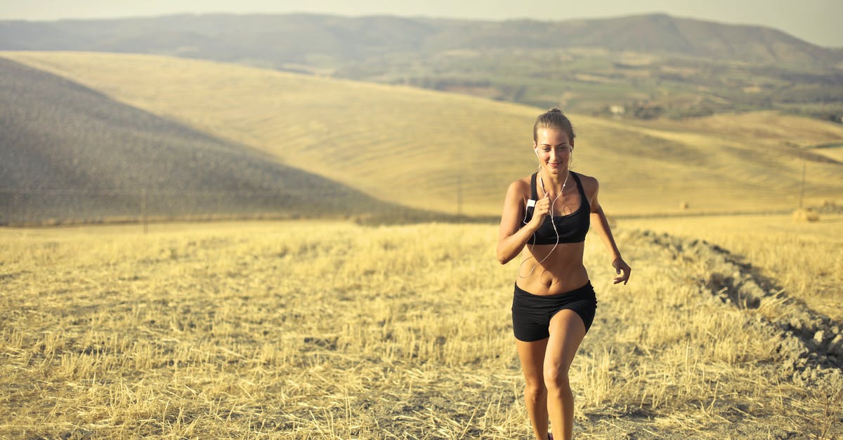 How to dry shirts using laundromats? - Powerful young female athlete in activewear running along hill on background of mountainous landscape and listening to music in earphones during cardio training