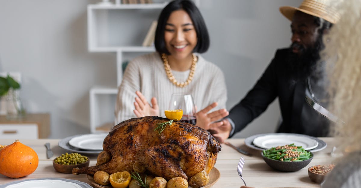 How to eat a meal with locals in Turkey? - Cheerful multiethnic people having dinner together at table with roasted turkey while celebrating Thanksgiving Day