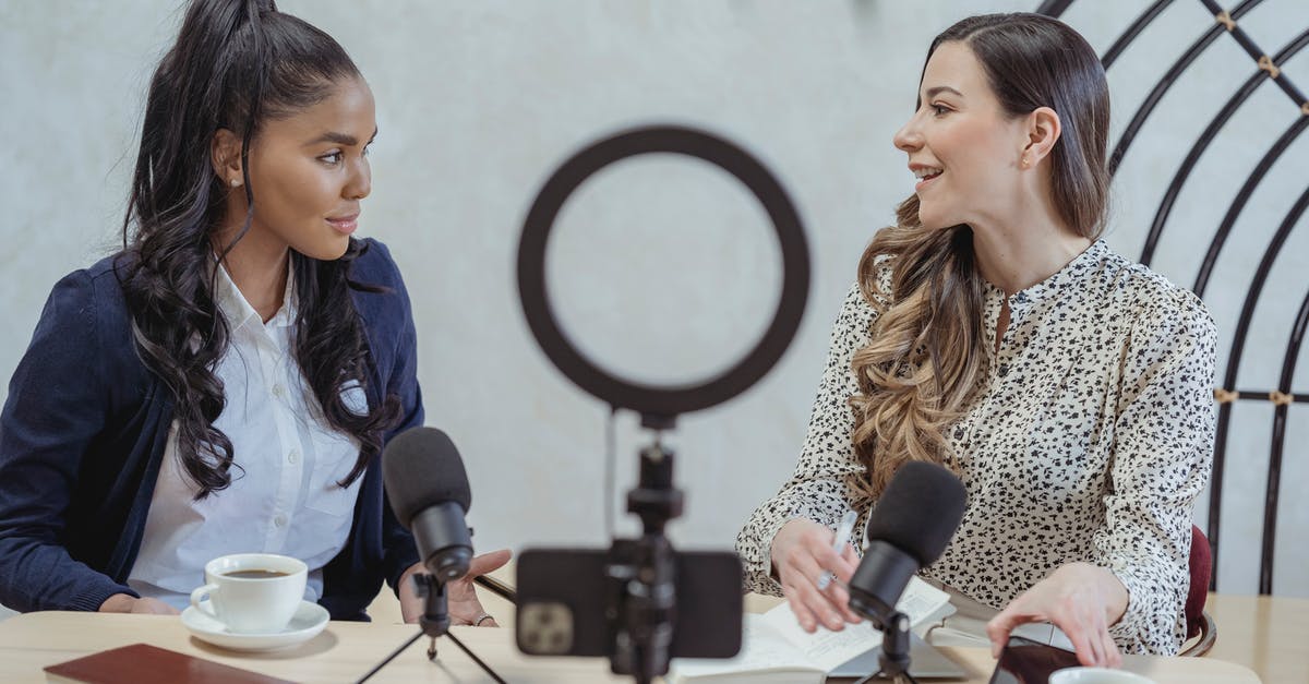 How to ensure tripod/camera safety when using remote [closed] - Positive blogger asking questions to African American speaker and recording interview on cellphone at table with microphones