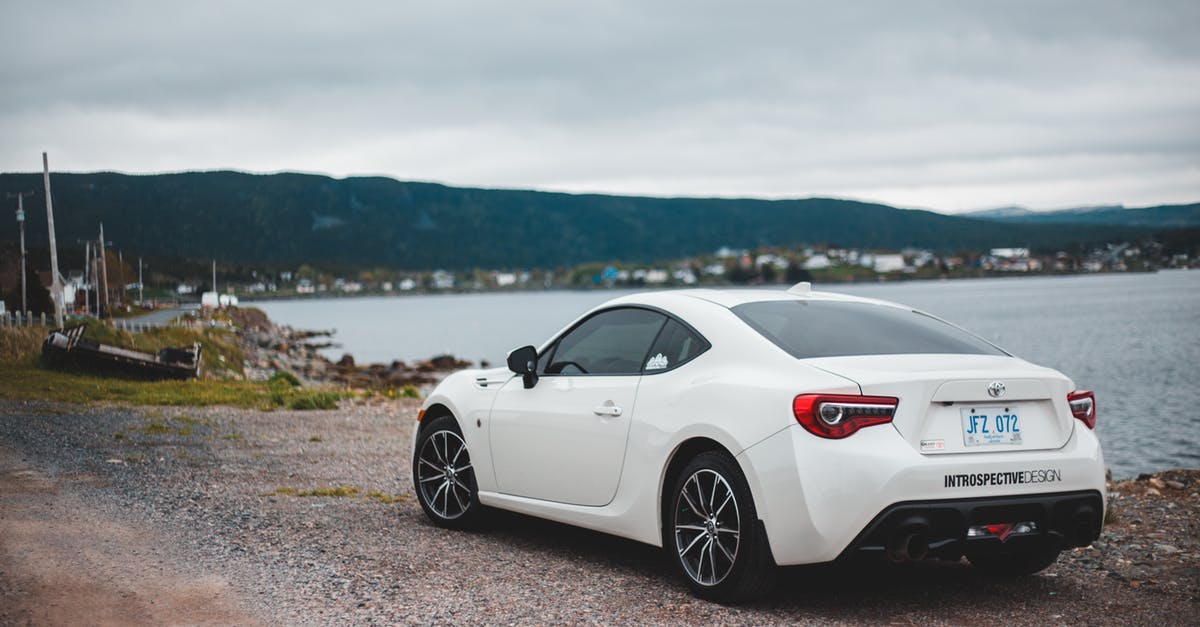 How to find a truck mechanic while traveling in New Zealand - Back view of modern stylish white automobile parked on gravel pond coast against small settlement on overcast day