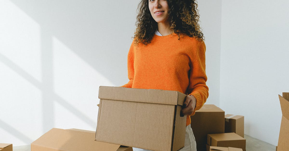 How to find accommodation when what you reserved appears to be overbooked, or worse, non-existent? - Young female arranging carton box and smiling at camera during relocation How to find accommodation when what you reserved appears to be overbooked, or worse, non-existent? - Young female arranging carton box and smiling at camera during relocation