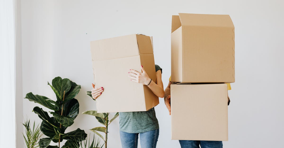 How to find neighboring apartments/self-catering accommodation? - Unrecognizable couple wearing jeans standing carrying stacked carton boxes out of apartment during renovation on daytime