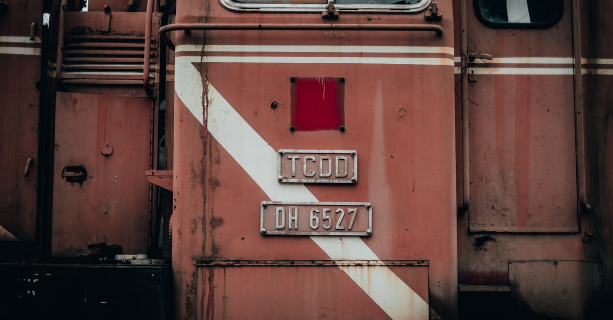 How to find out train track number in Spain? - Wagon of industrial red old timer metal train with plate and window near door located on street in railway station