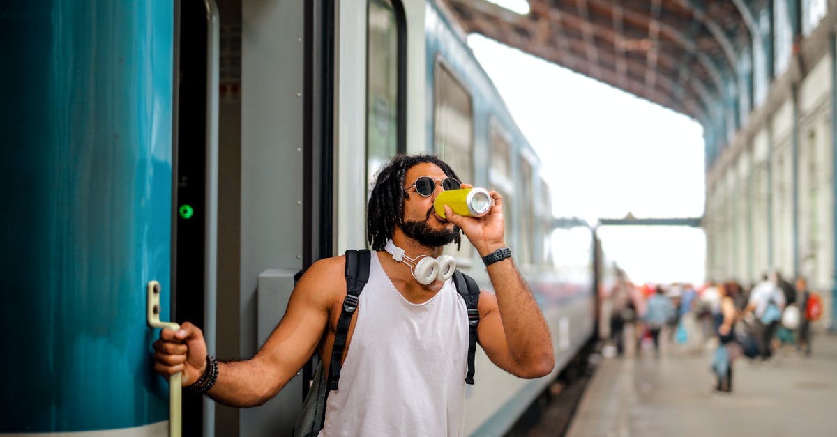 How to find public drinking fountains when travelling? - Man Drinking From Can While Standing Near train