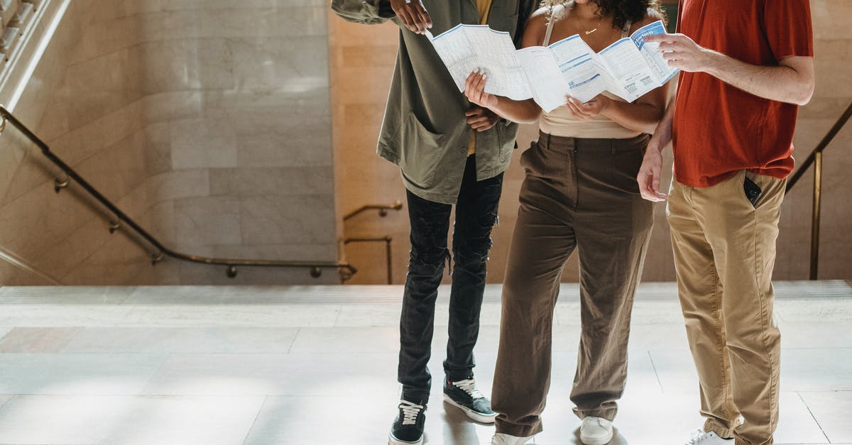 How to find the Flixbus timetable for a specific route? - Concentrated young Hispanic lady reading map while standing near staircase of old building during vacation with crop multiethnic male friends