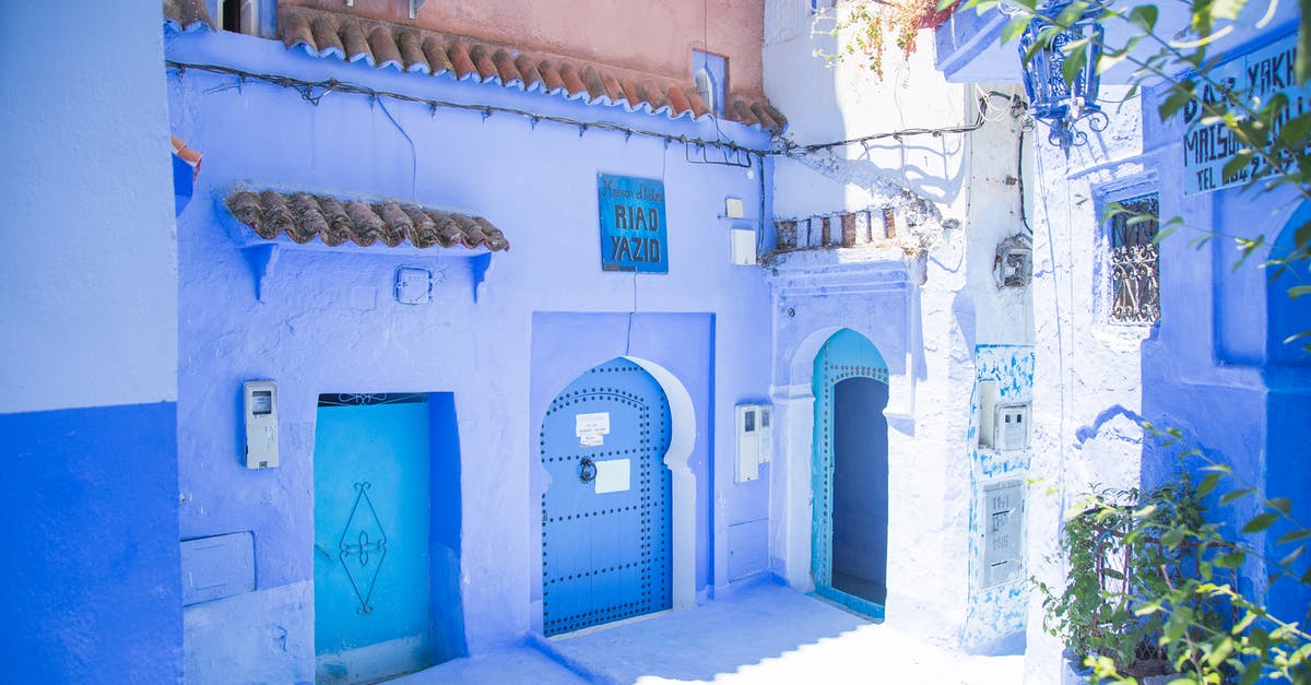 How to find the nearest location which has sunny forecast - Blue exterior of house with doors located under sunlight on street with green plants in city of Morocco in summer