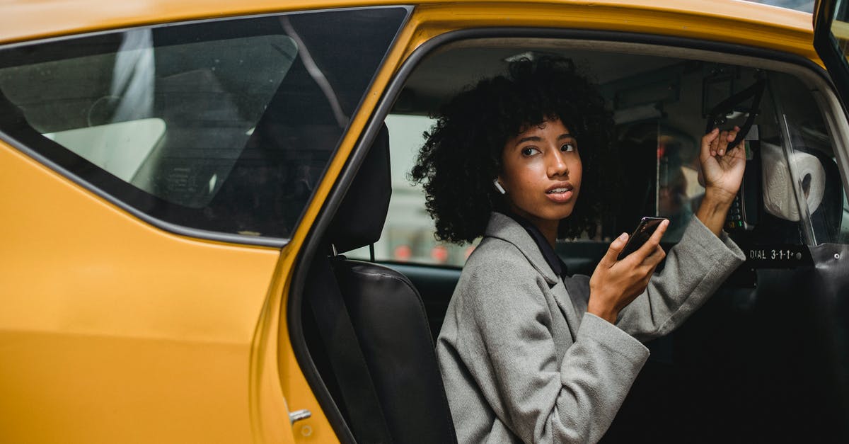 How to get a taxi on Prague streets? - African American woman getting out of yellow cab